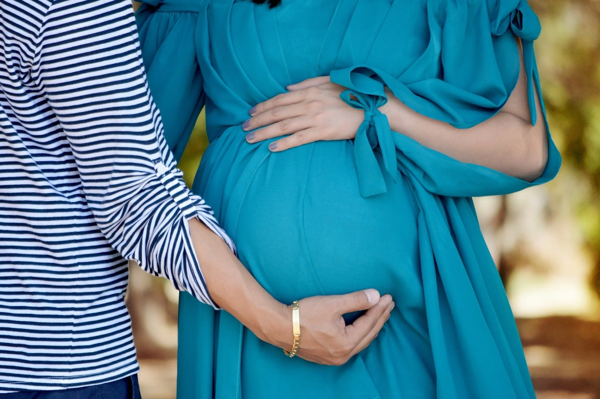pregant woman in a blue dress poses for a photo