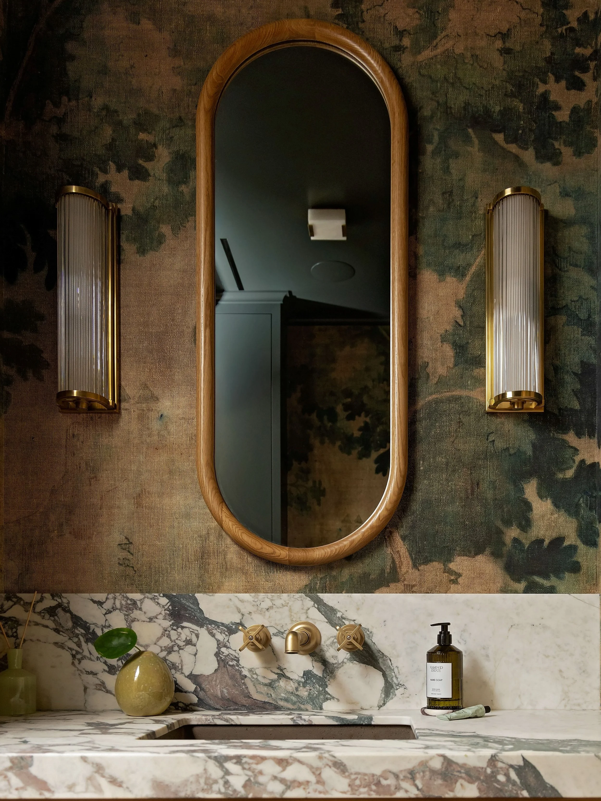 Located just off the condo&rsquo;s entry, this compact powder room needed an identity of its own while still feeling connected to the rest of the home. 

A grass cloth mural wallpaper wraps the room with an atmospheric landscape. The reeded wood vani