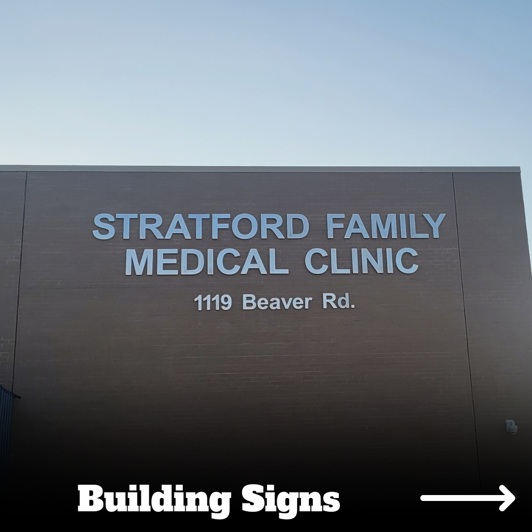 Sign on a building reading 'Stratford Family Medical Clinic, 1119 Beaver Rd.' with an arrow labeled 'Building Signs' pointing to the right.