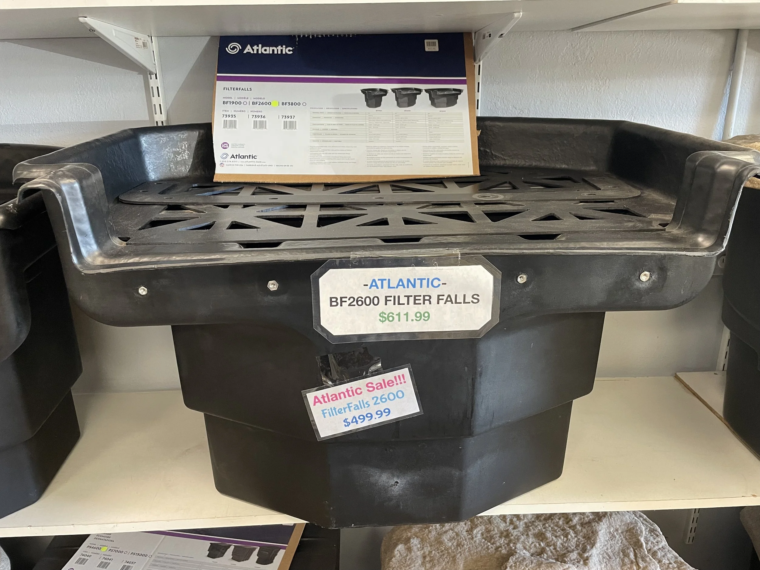 A black plastic filter fall tray for a filtration system, labeled as Atlantic BF2600, priced at $611.99, displayed on a shelf with an additional sign indicating it is on sale for $499.99.