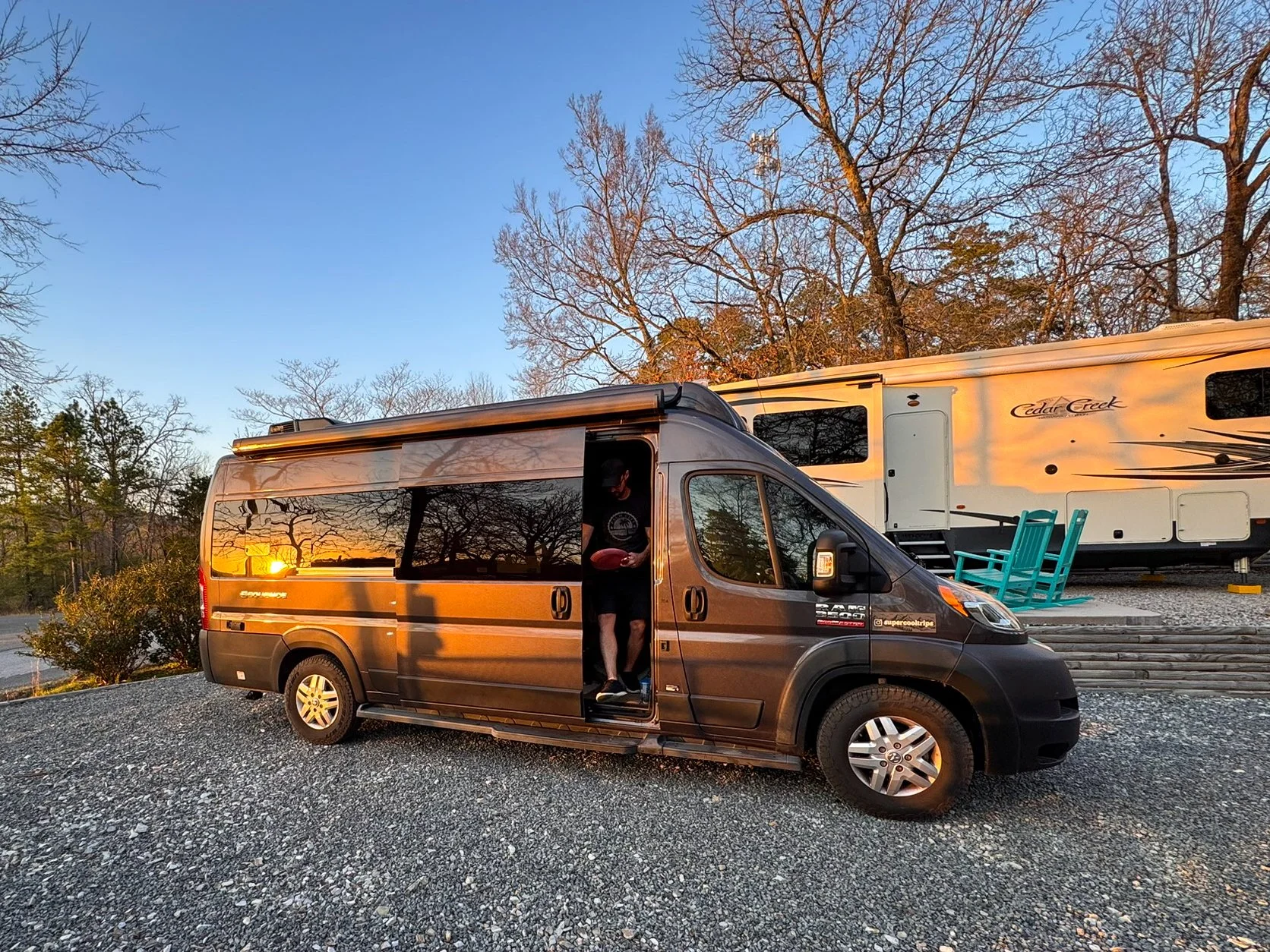 A man prepares to exit a camper van at Hot Springs National Park KOA in Arkansas as the sunset reflects in the vehicle’s windows.