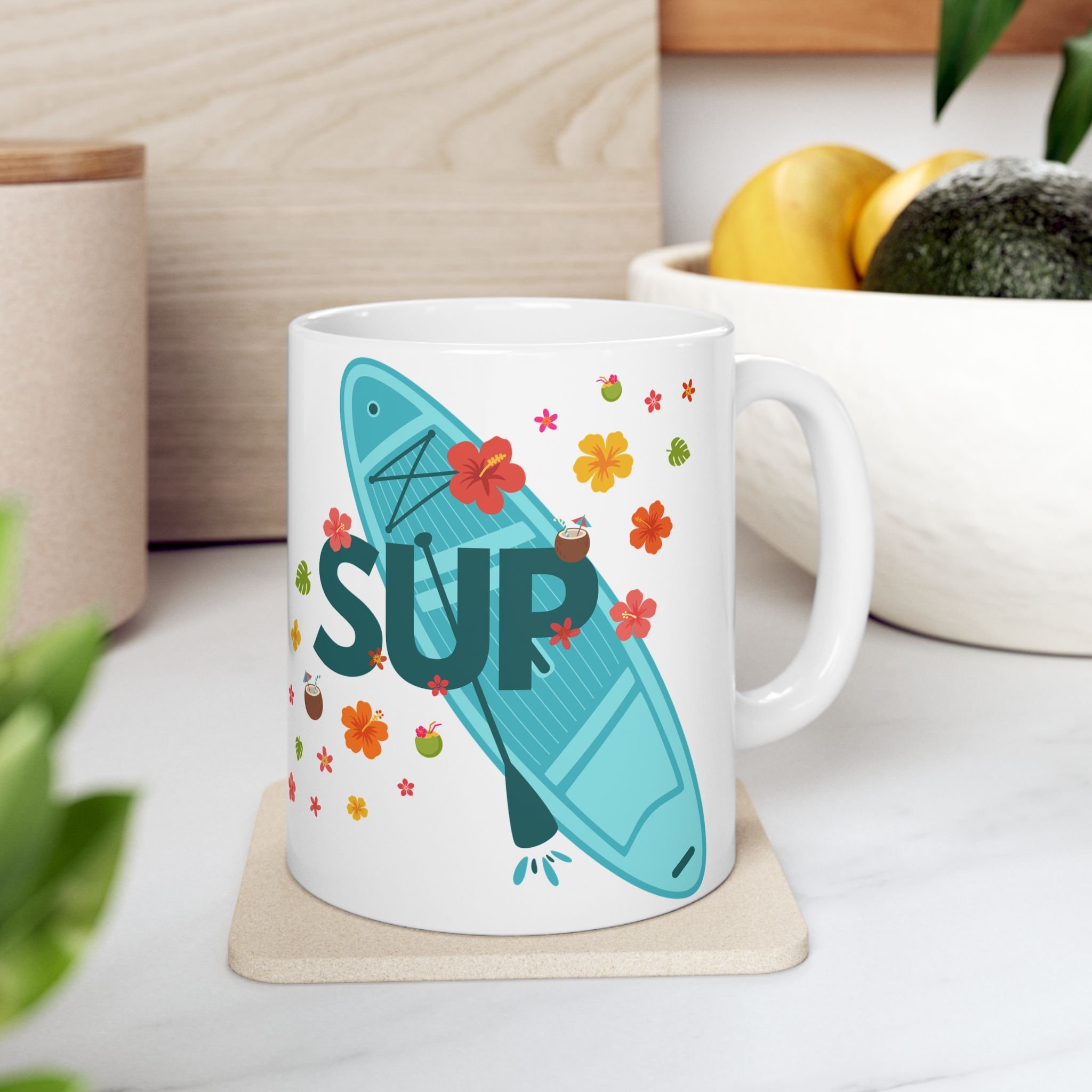 This stand-up paddle board mug, featuring tropical colors, flowers, foliage and drinks, will brighten any kitchen.