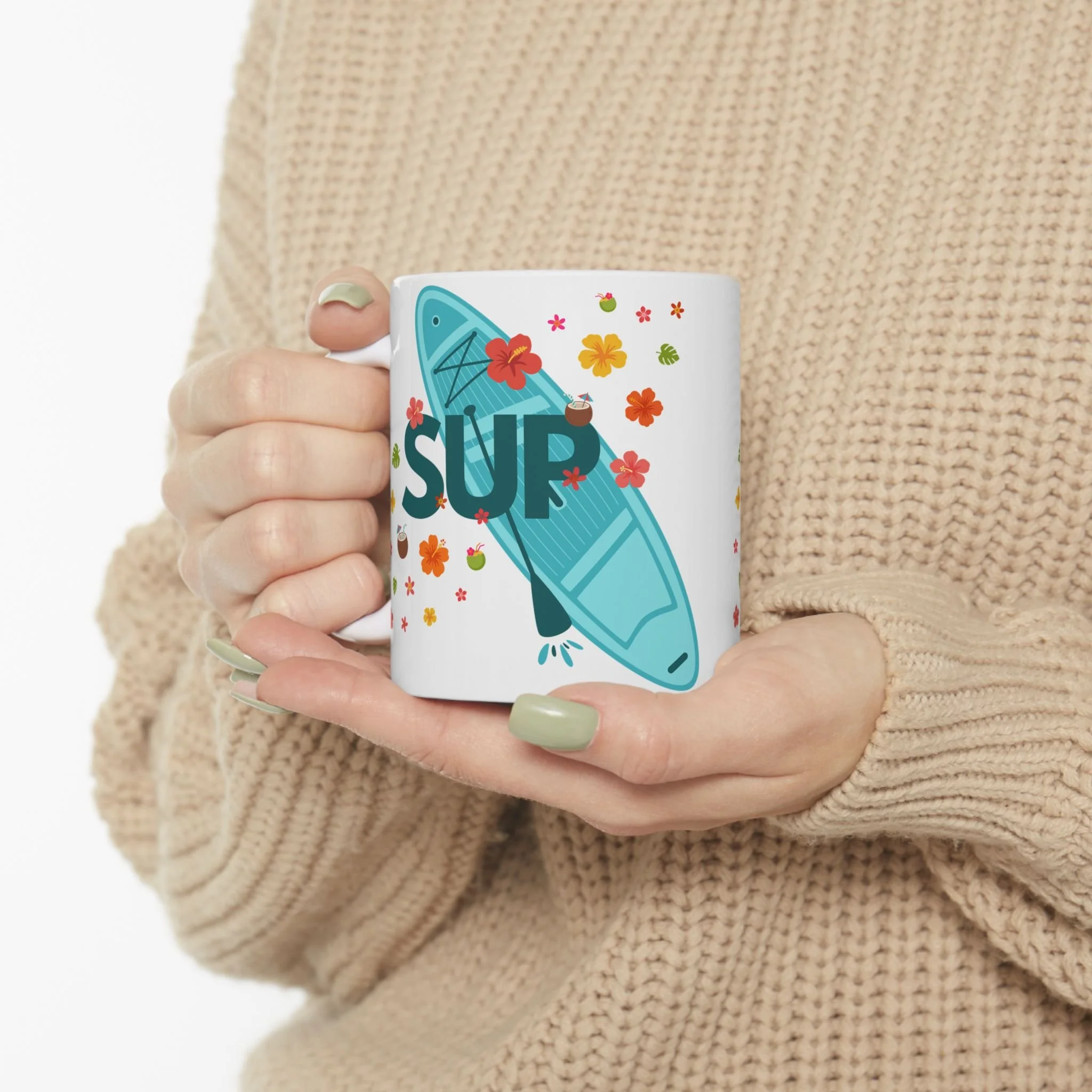 A woman warms her hands with our stand-up paddle board mug, featuring tropical colors, flowers, foliage and drinks.