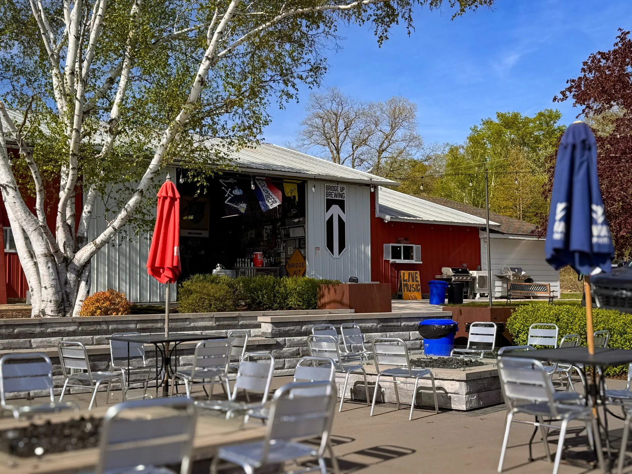 Exterior of Bridge Up North Taproom at The Cherry Hut in Fish Creek, Wisconsin, with a beer garden and garage-style building.