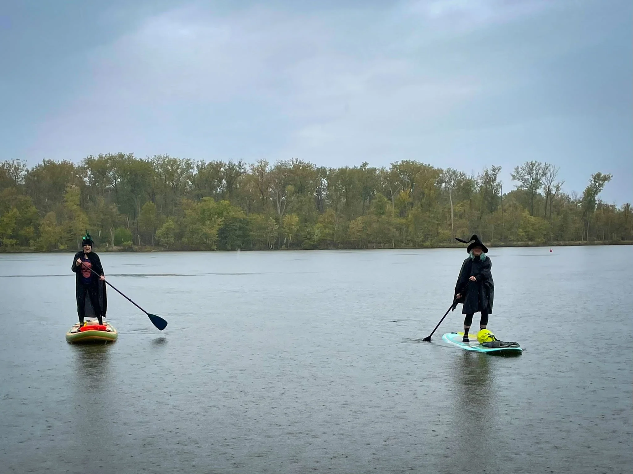 Two women dressed as witches paddle board on a rainy day in Saint Louis, Missouri.