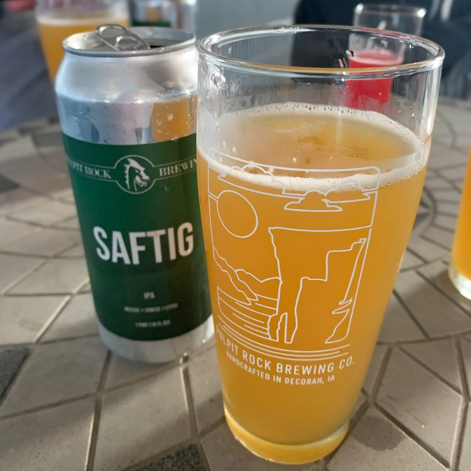 Can of Saftig IPA from Pulpit Rock Brewing beside a glass of the poured beer, with the brewery's Norway-inspired logo visible on the glass.