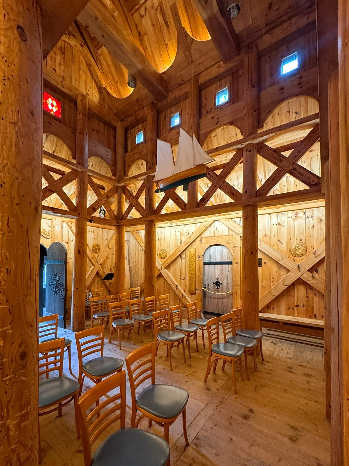 Interior of Washington Island Stavkirke in Wisconsin, showing tall wooden staves and timber cross-braces arranged in St. Andrew’s crosses.