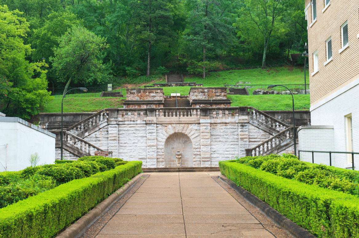 Stone fountain with a seashell-shaped basin in an alcove of the Grand Promenade staircase in Hot Springs National Park.