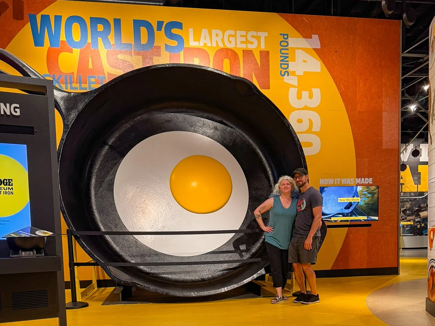 Two people stand beside the world's largest cast iron skillet at the Lodge Museum of Cast Iron in South Pittsburg, Tennessee.