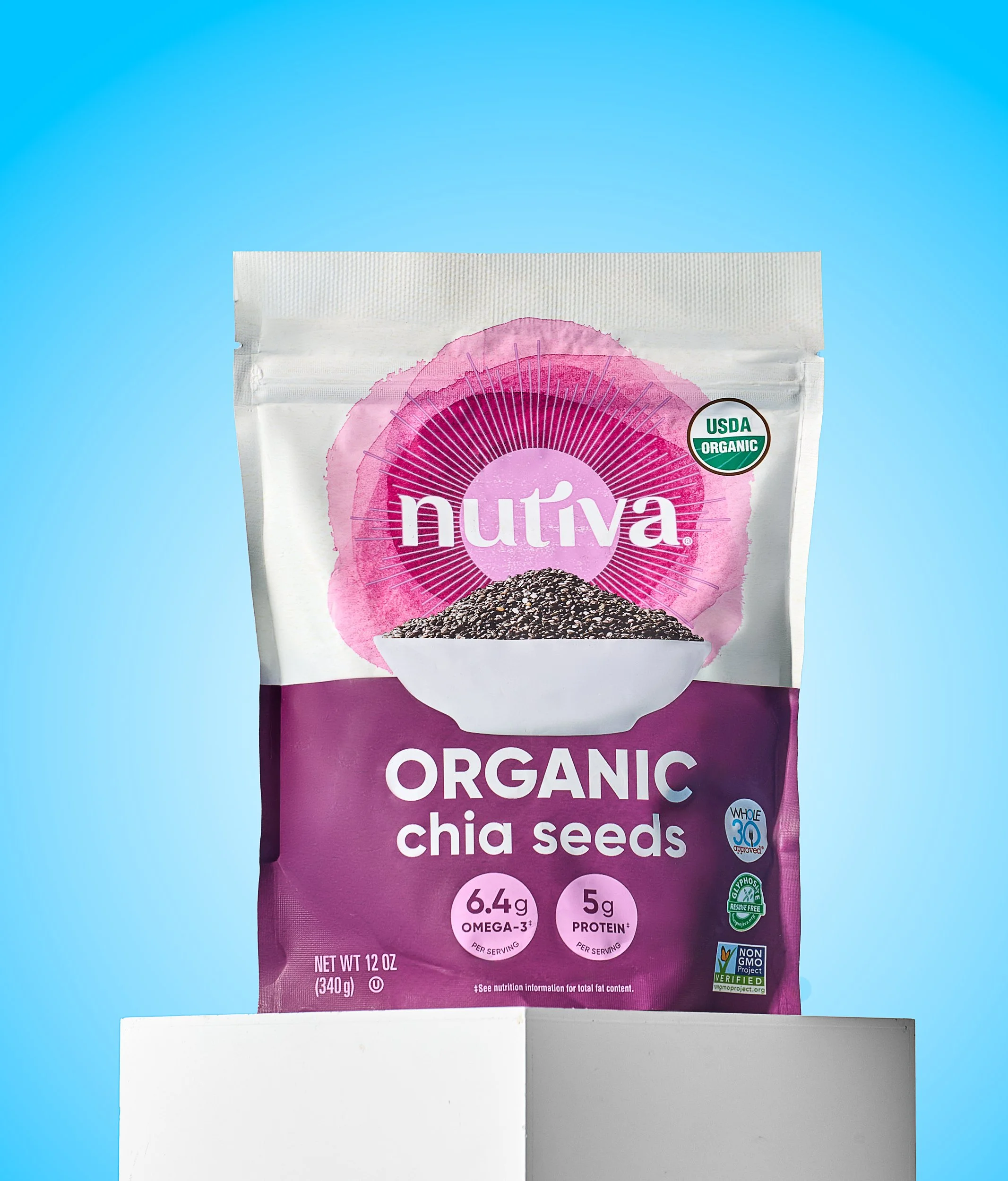 A package of Nutiva organic chia seeds with a white bowl of black and white chia seeds in front of it, set against a blue background.