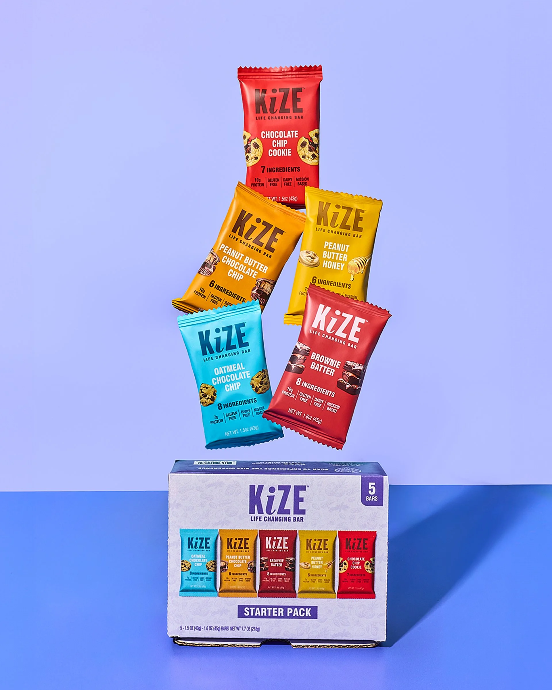 An assortment of five KiZE life-changing snack bars in various flavors, including chocolate chip cookie, peanut butter chocolate chip, peanut butter honey, oatmeal chocolate chip, and brownie batter, with a box containing five bars.