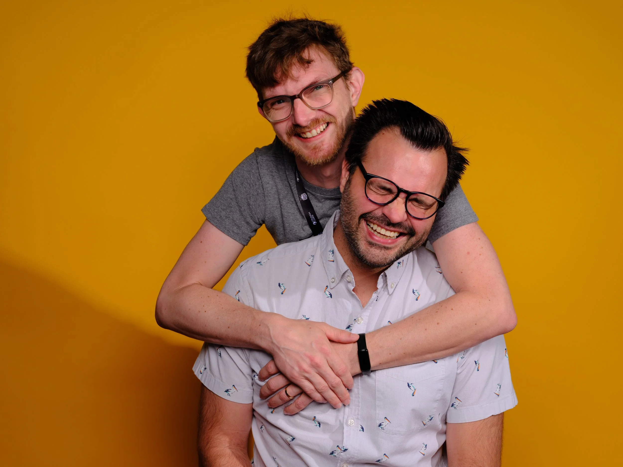 Julian and Trace cuddle in front of an orange backdrop