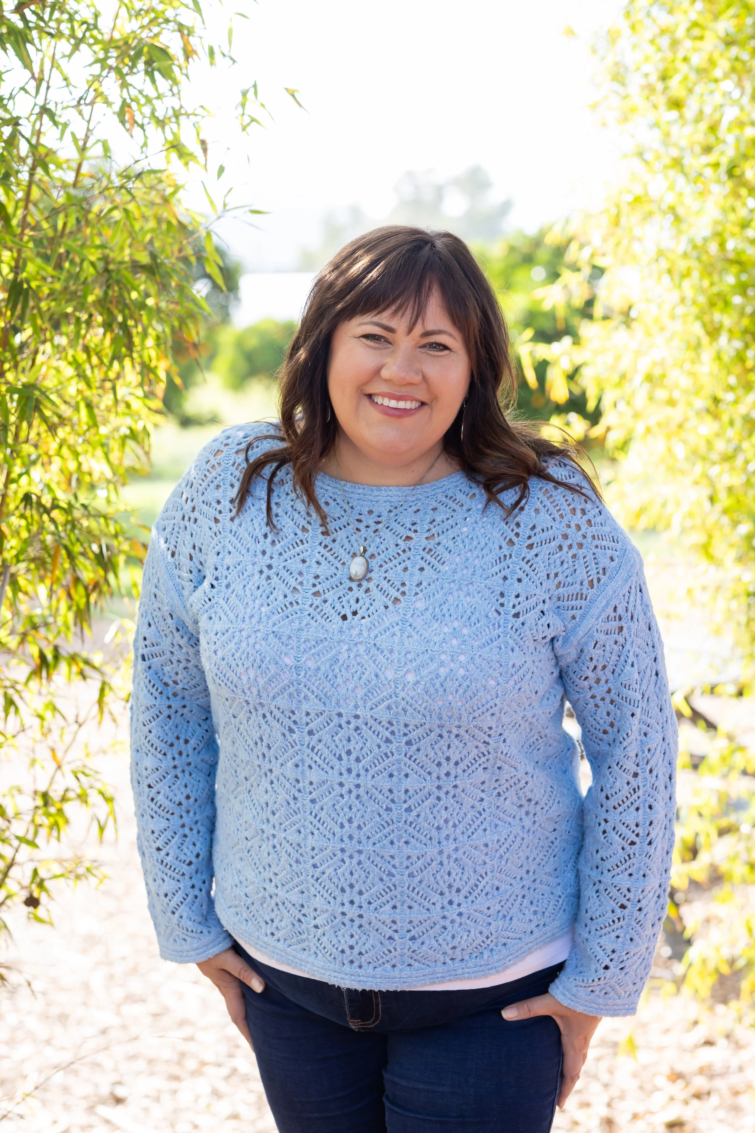 Julie smiling outdoors in a blue sweater