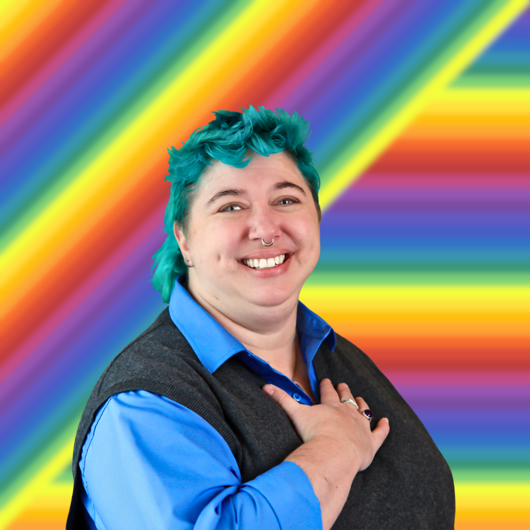 Mara with teal hair, smiling with hand on heart with rainbow background