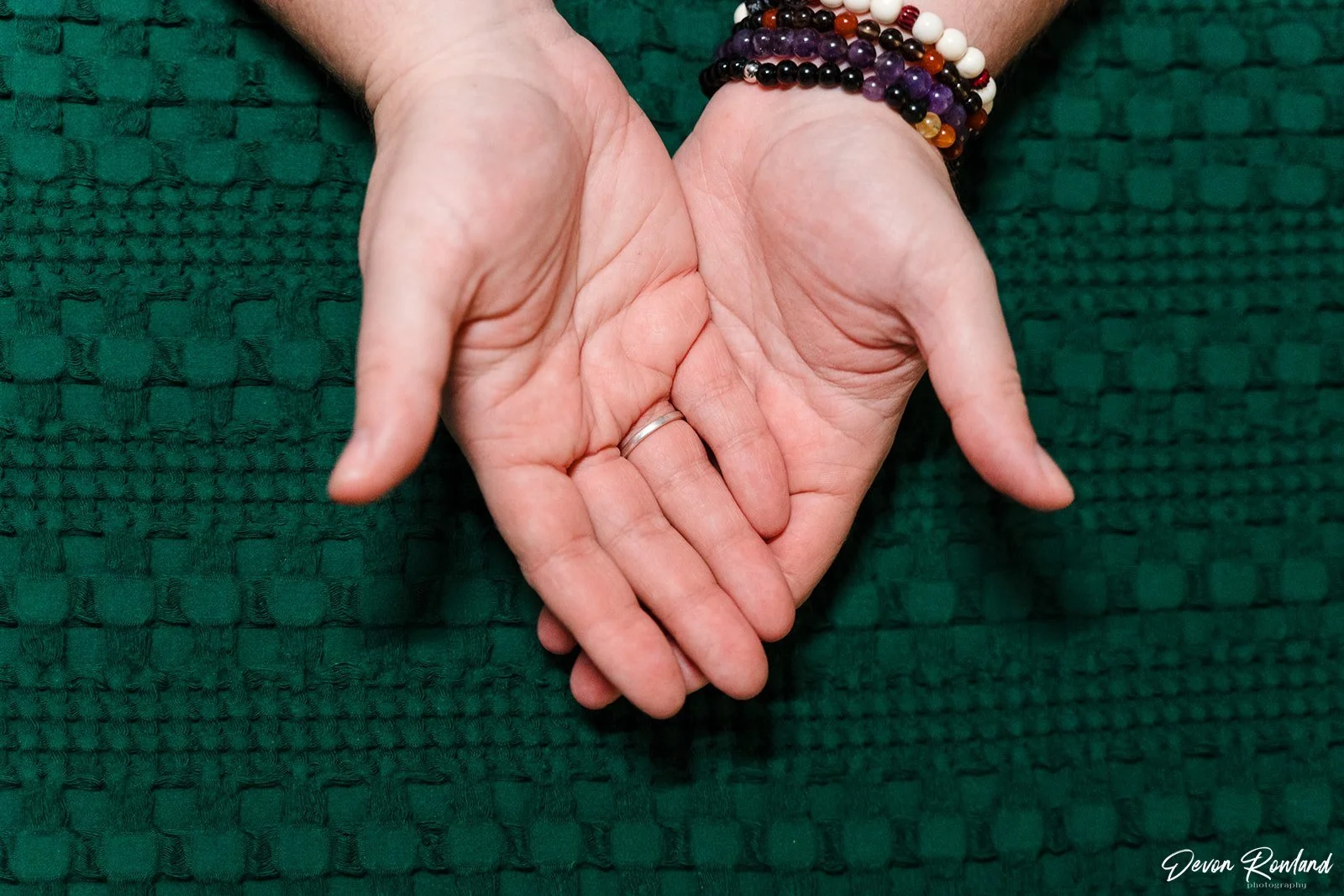 Mara's hands resting on a textured blanket with colorful bracelets on one wrist.
