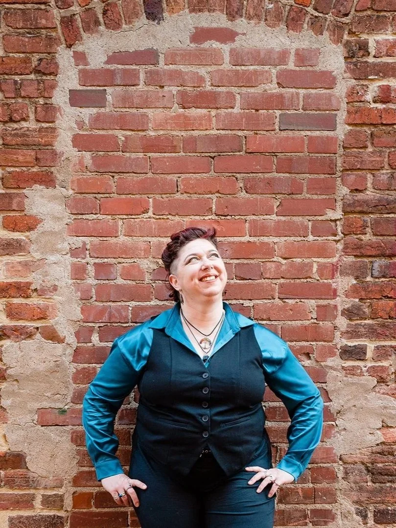 mara standing against a brick wall, looking inquisitive