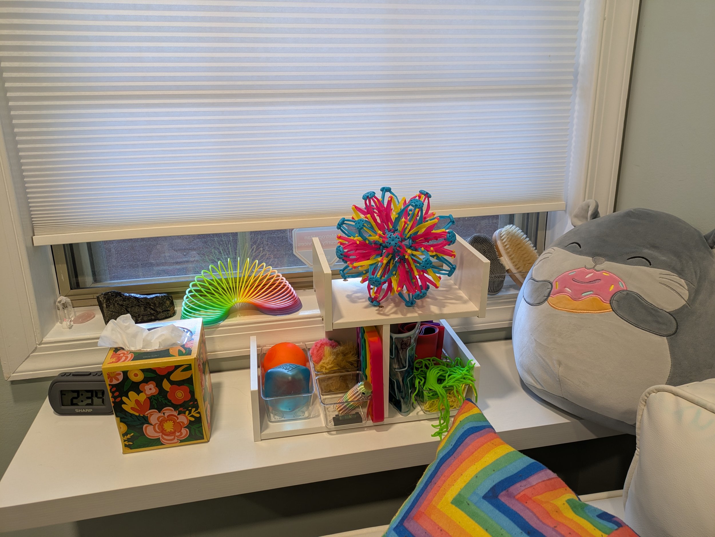 A variety of fidgets and stim toys are next to the couch for you to use