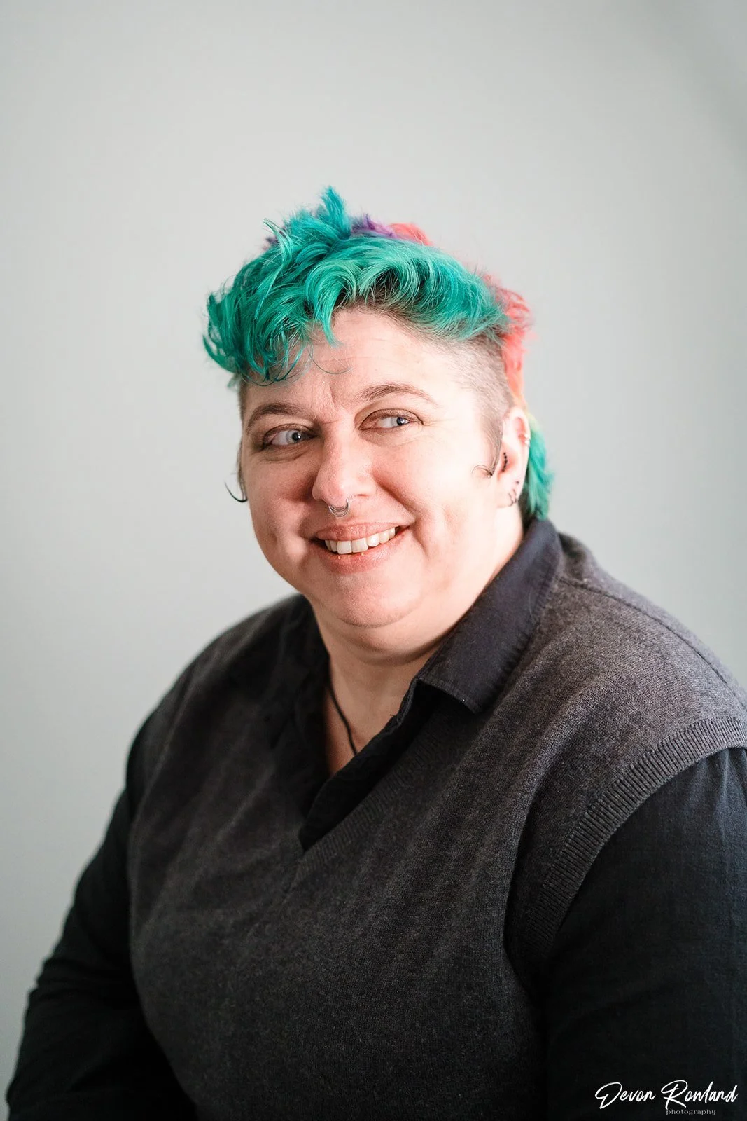 mara with teal and rainbow short hair smiles