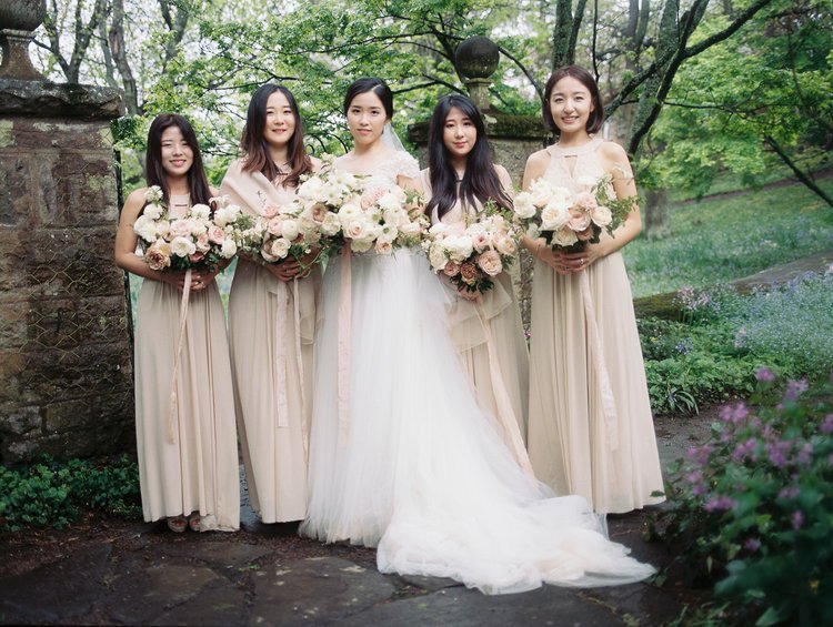 Bride with bridesmaids holding bouquets in a garden setting.