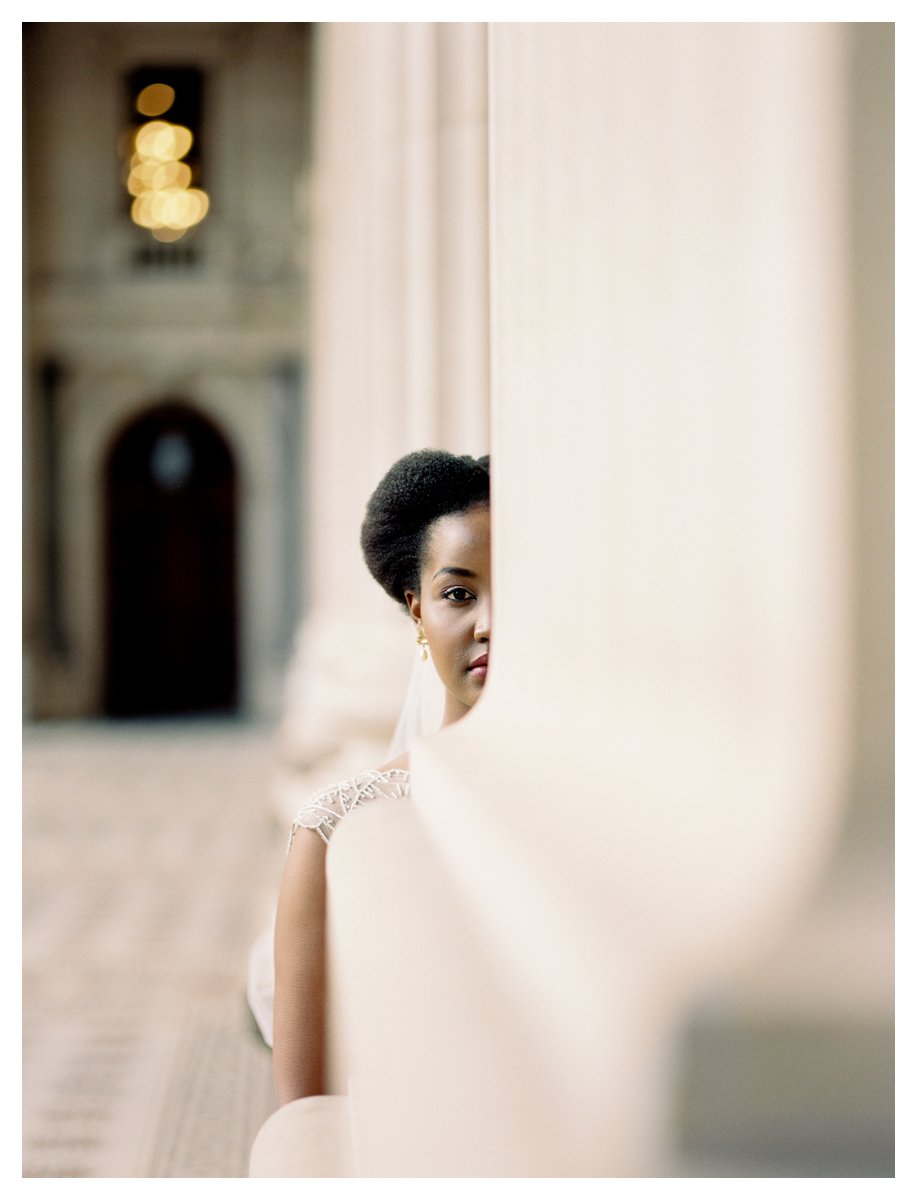 Woman partially obscured by a wall in an ornate hallway