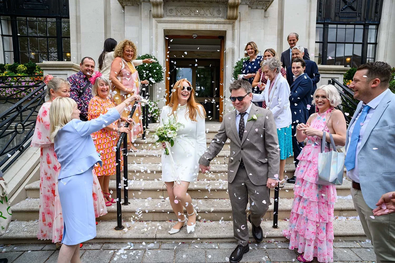 A couple covered in confetti on the steps of Islington Town Hall. London wedding photography by Steve Bagness