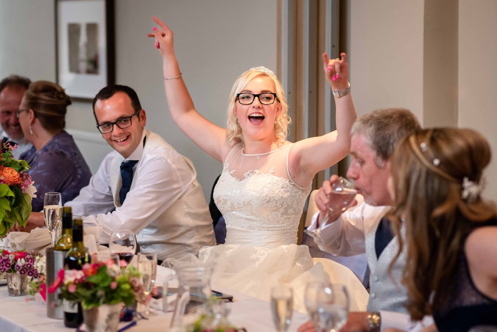 Bride cheers during a wedding speech at Warbrook House