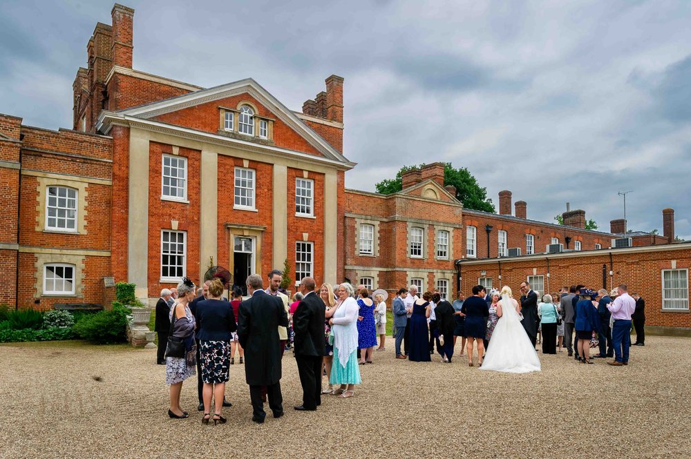 Wedding guests mingle at the front of Warbrook House