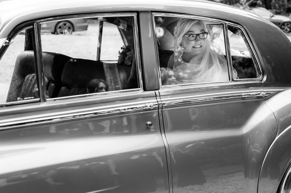 A bride looks excited as she arrives in her wedding car