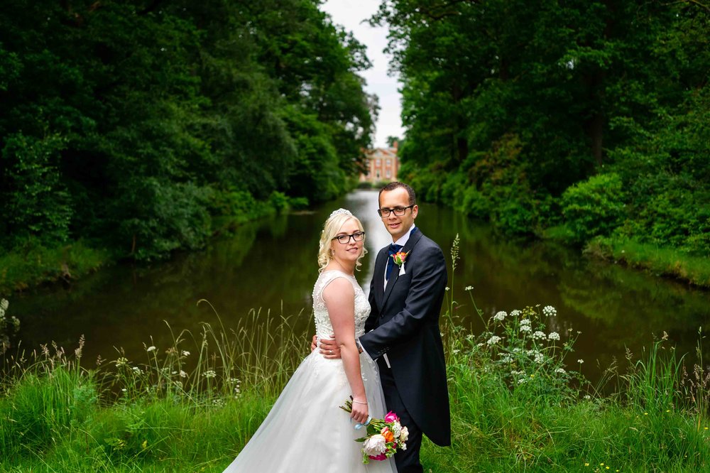 Bride and Groom pose by the lake at Warbrook House