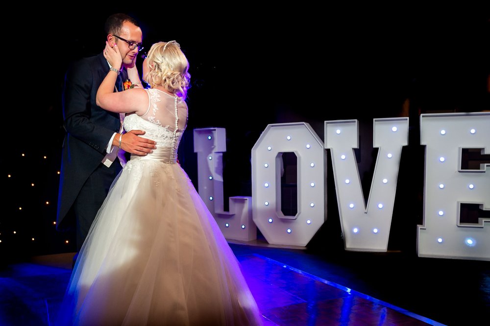 Bride and Groom dance in front of Love letters