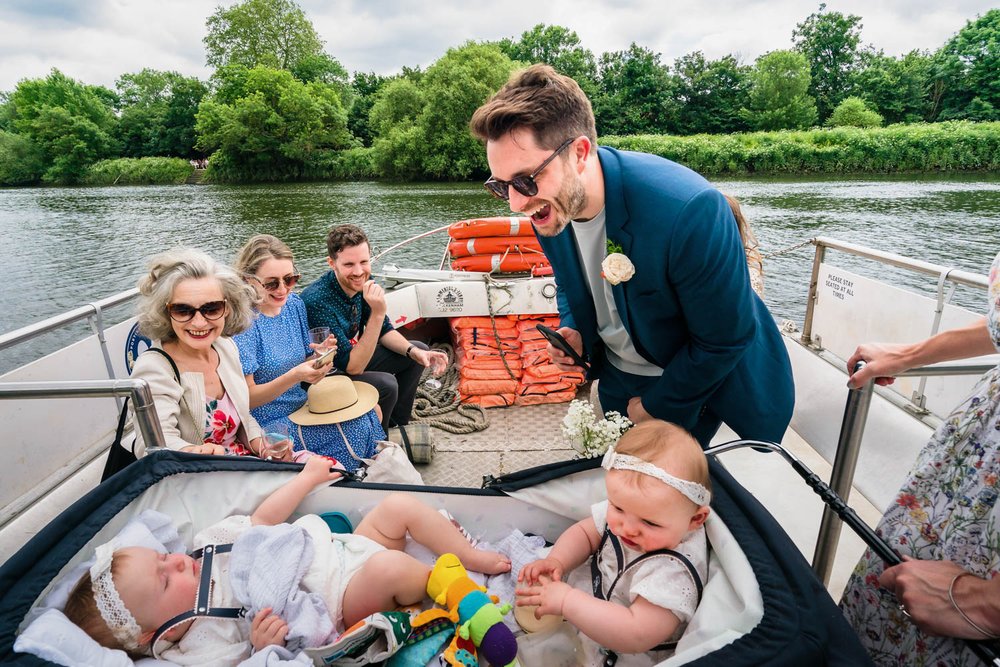 Groom looks at twin babies on Thames ferry crossing