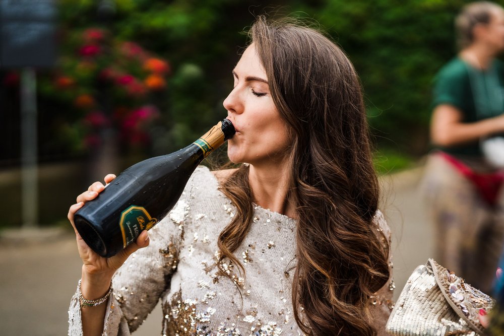 Bride drinks from champagne bottle outside Richmond pub
