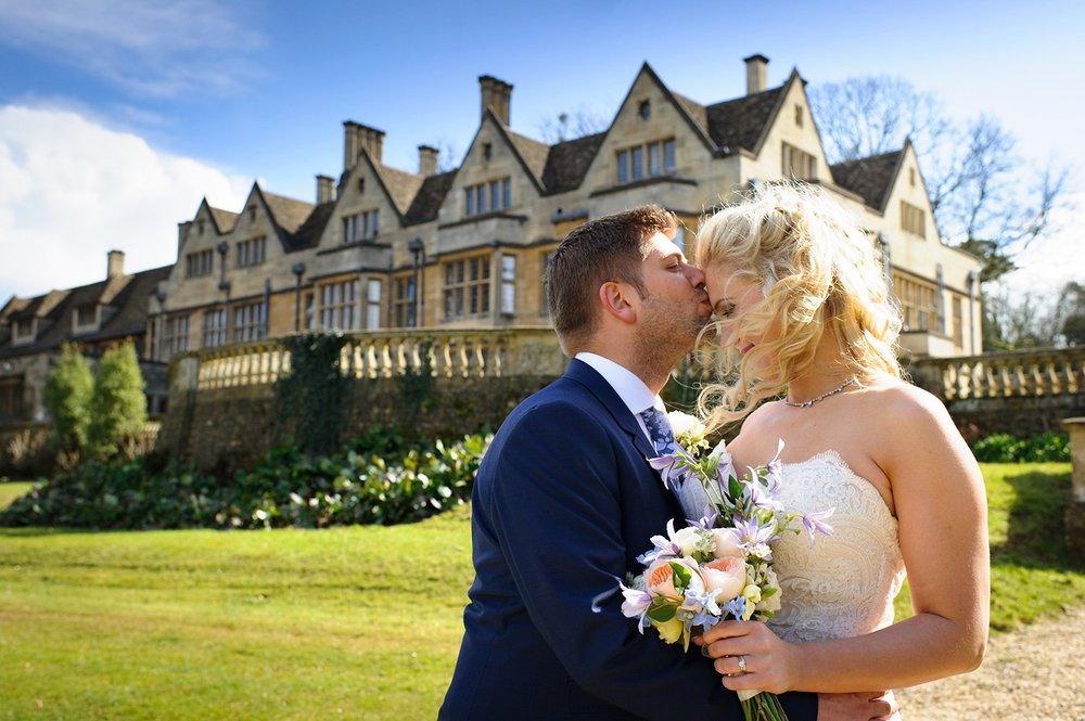Groom kisses bride in the grounds of Coombe Lodge wedding venue