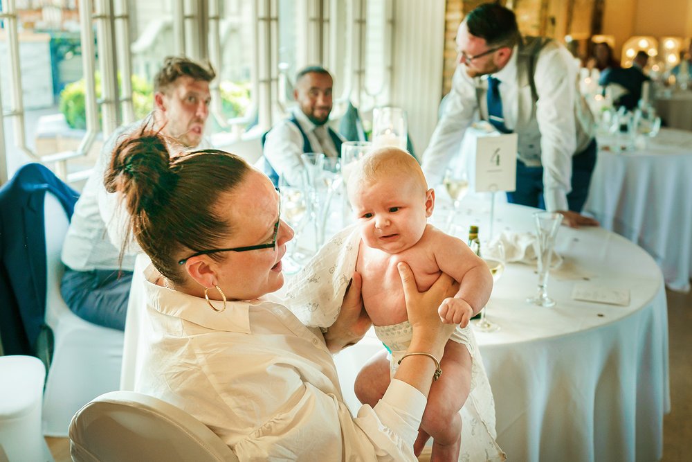 Grandmother holds baby at Friern Manor wedding