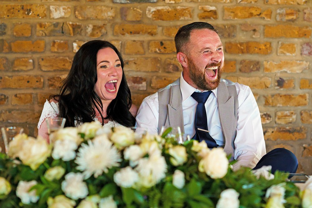 Bride and Groom laugh at speeches at Friern Manor