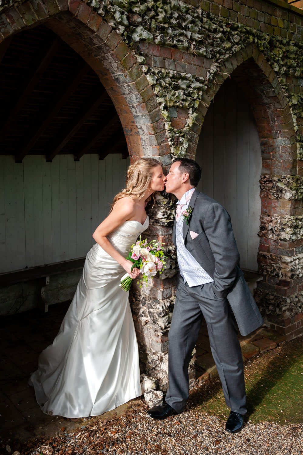 Newlyweds kiss under arches at Donnington Valley Hotel, Newbury