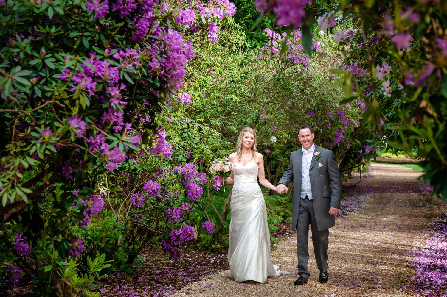 Bride and Groom walk through flowers at Donnington Valley Hotel, Newbury