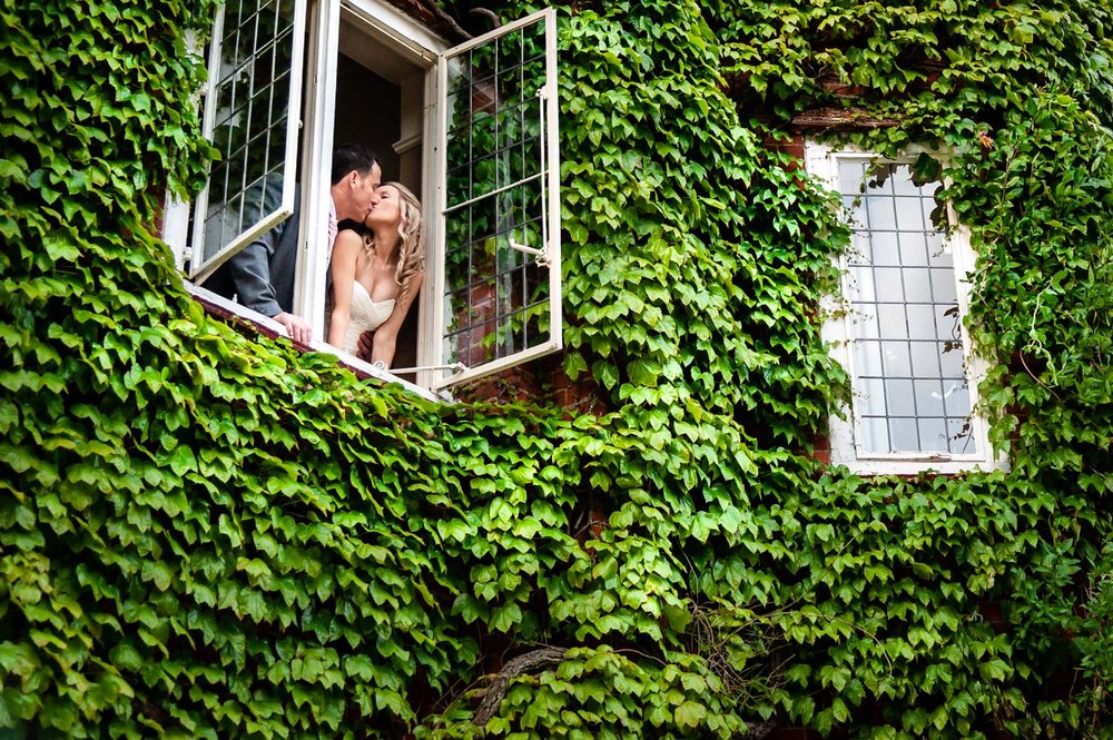 Bride and Groom in a vine covered window at Donnington Valley Hotel
