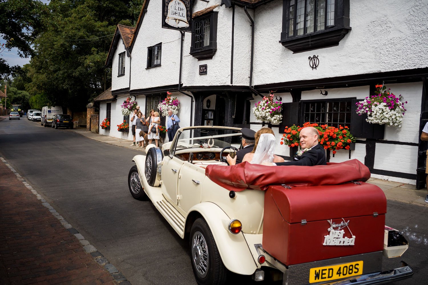 Married couple leave a wedding at The Olde Bell in a vintage car