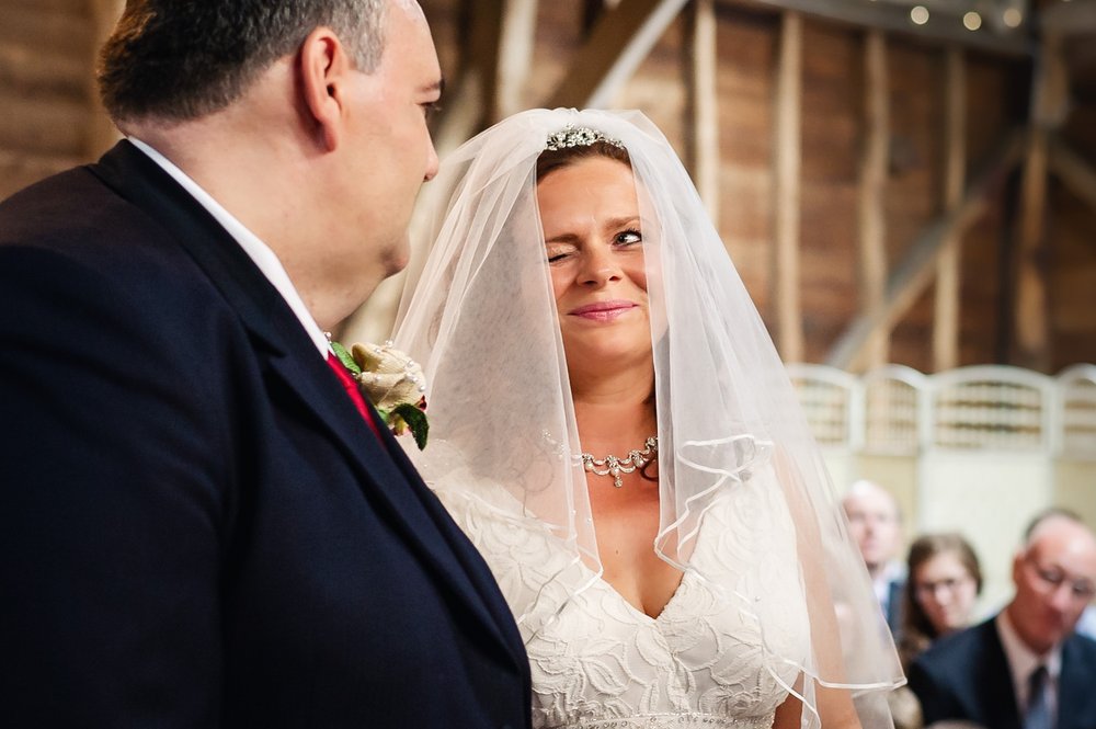 Bride gives the groom a reassuring wink during wedding ceremony at Herons Farm