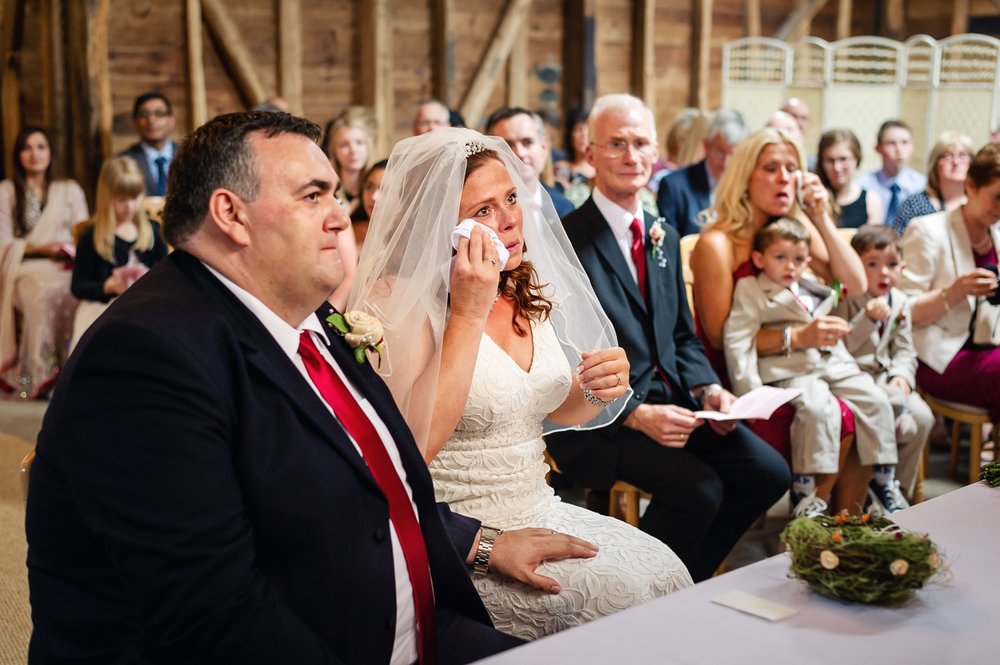 Bride wipes away tear during a Herons Farm wedding ceremony