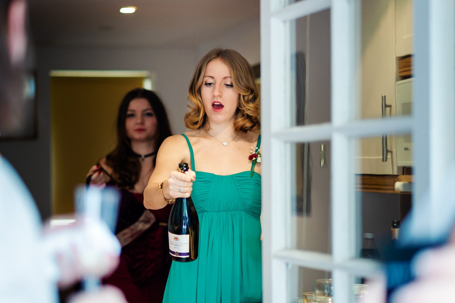 Bridesmaid opens a bottle of champagne