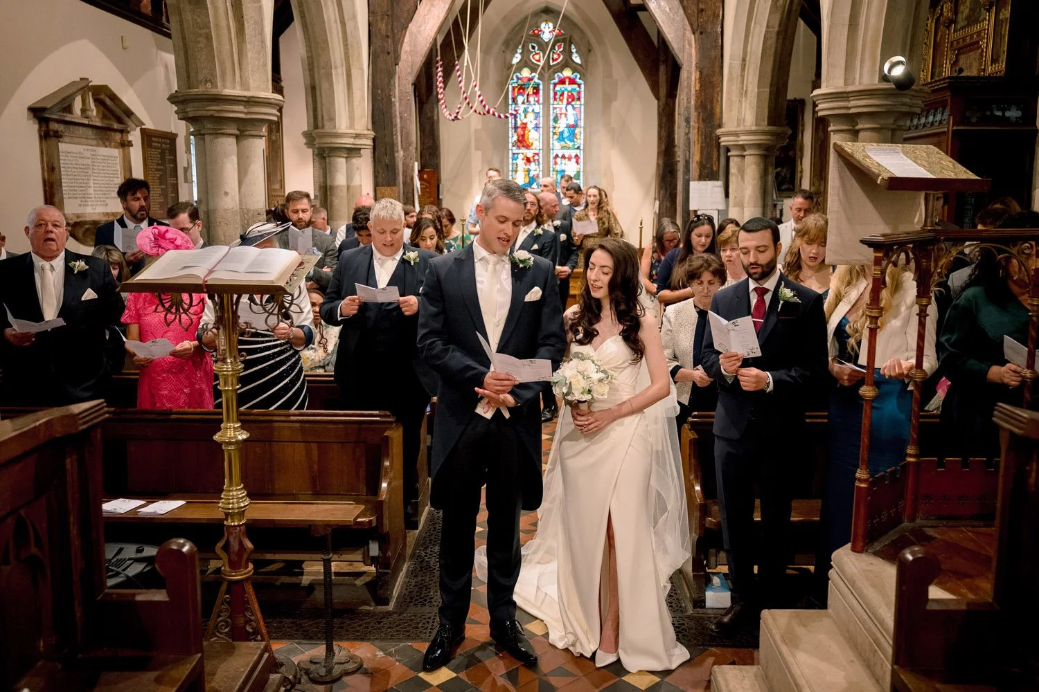 Bride &amp; Groom sing hyms during their wedding ceremony at All Saints Church Hutton