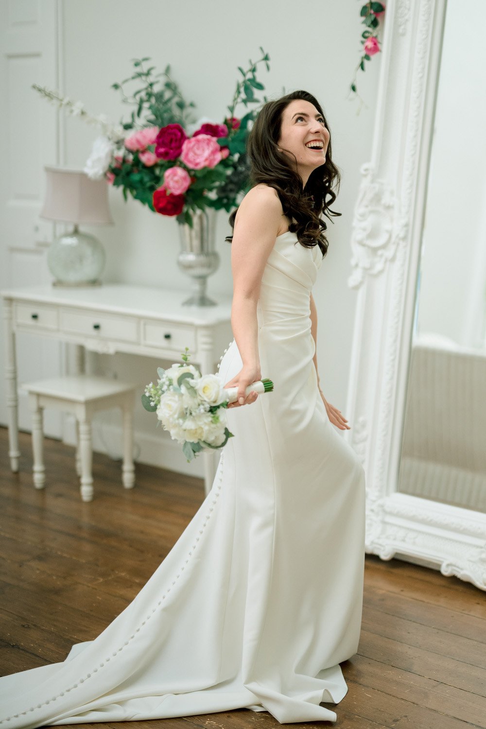 A bride joyfully plays in the huge bridal prep room at Hutton Hall in Essex