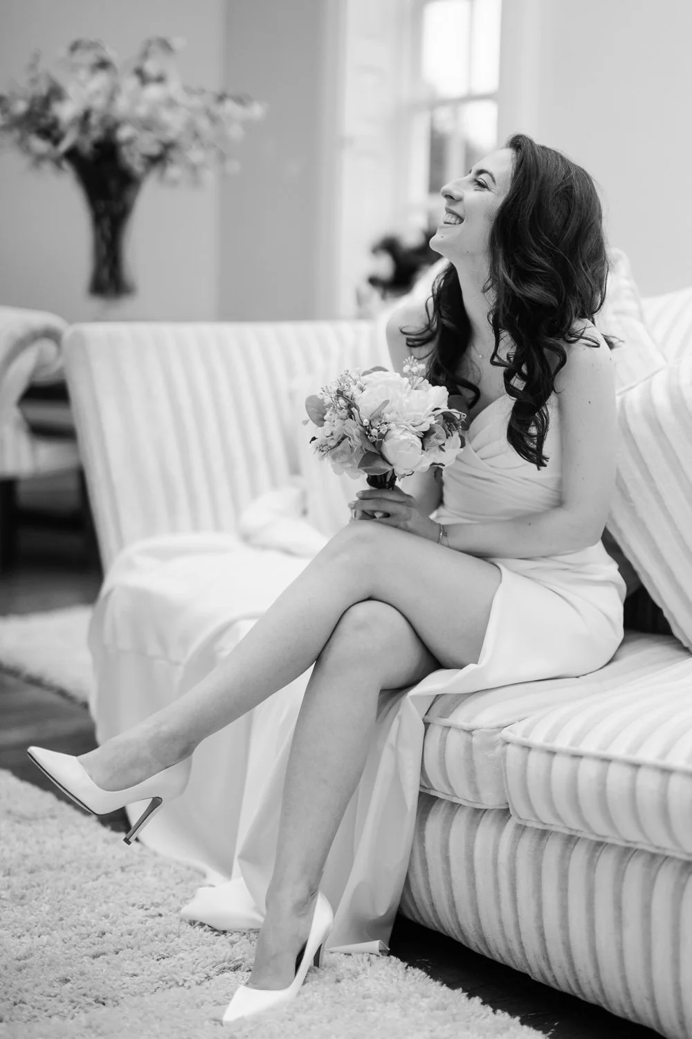 A bride kicks back and laughs on a couch at Hutton Hall in Essex