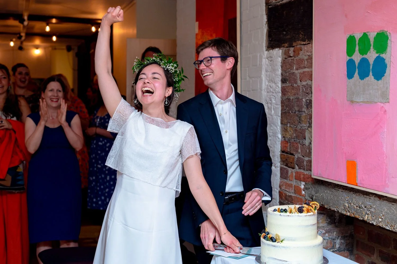 A bride punches the air as she cuts the wedding cake at Lauderdale House in Highgate, London
