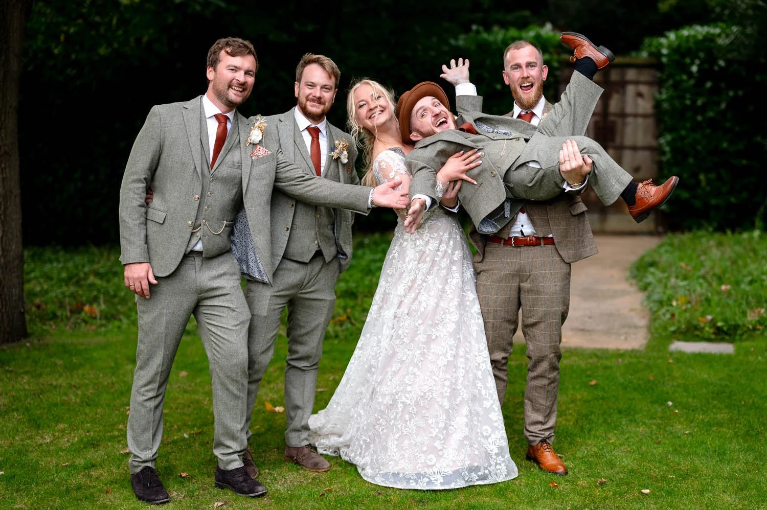 Groomsmen and the bride hold aloft best man, actor Leigh Gill, at Millbridge Court. Photograph by Steve Bagness Photography
