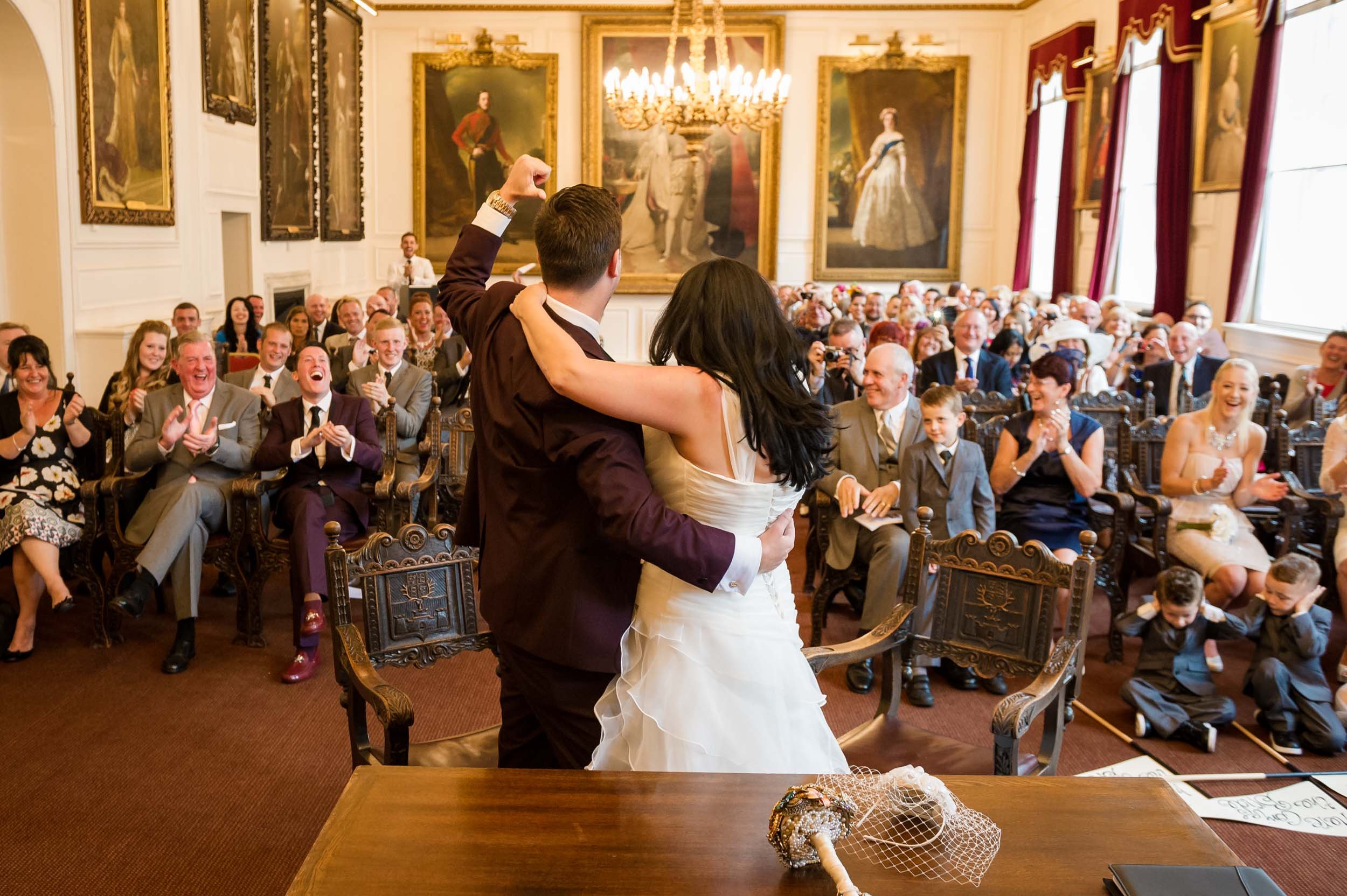 Groom punches the air at a wedding at Windsor Guildhall