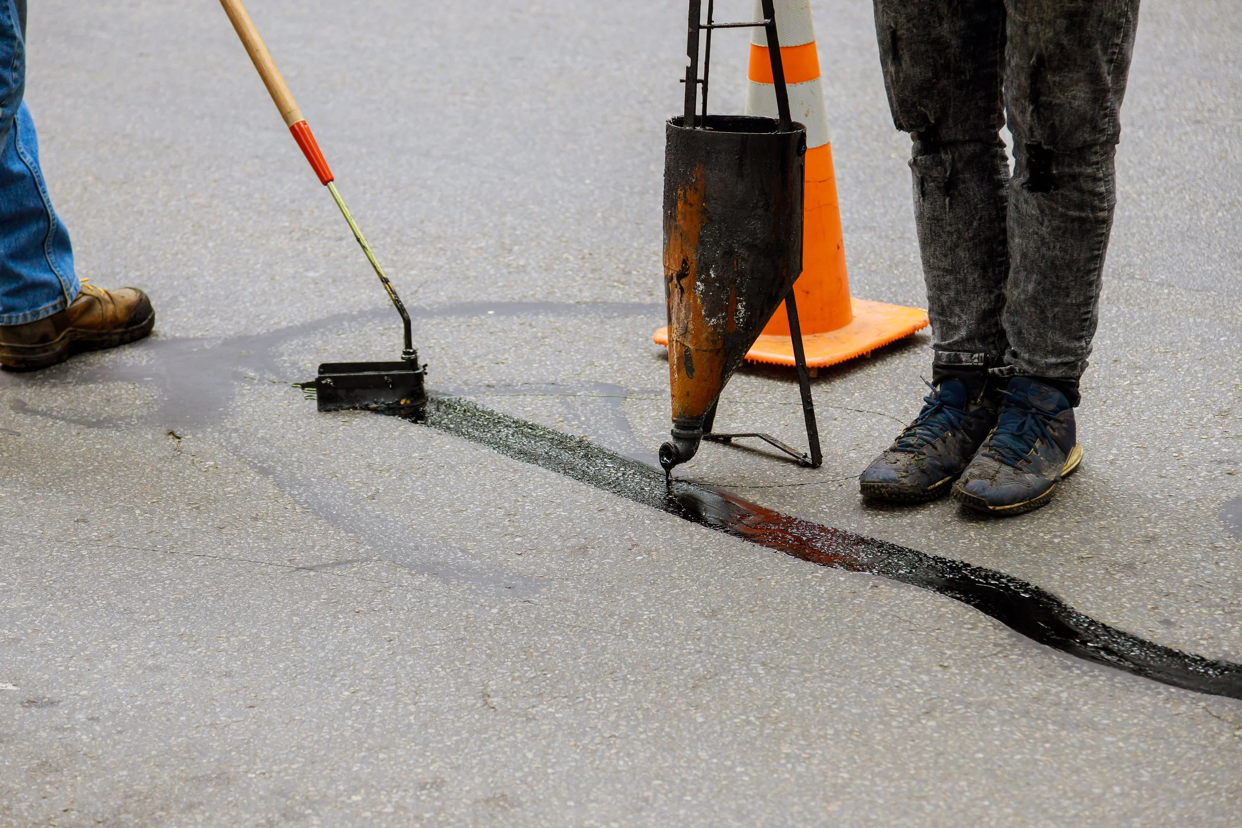 Men sealing cracks in a road.