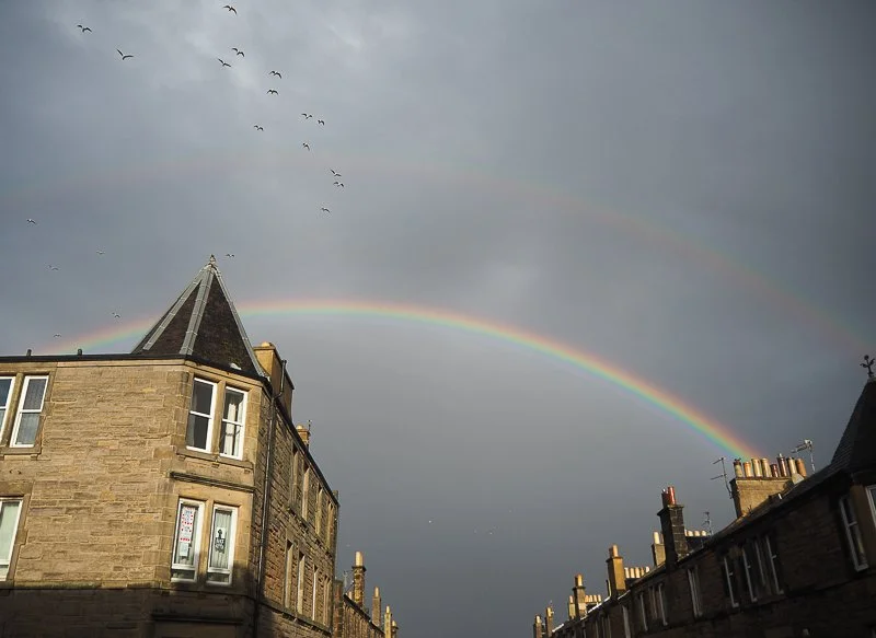Rainbow in a grey sky of Edinburgh, above tenment flats